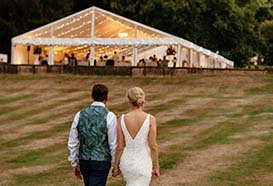 Bride and groom walk to their marquee