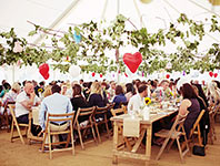 Wedding tent with dark wood tables and wooden chairs